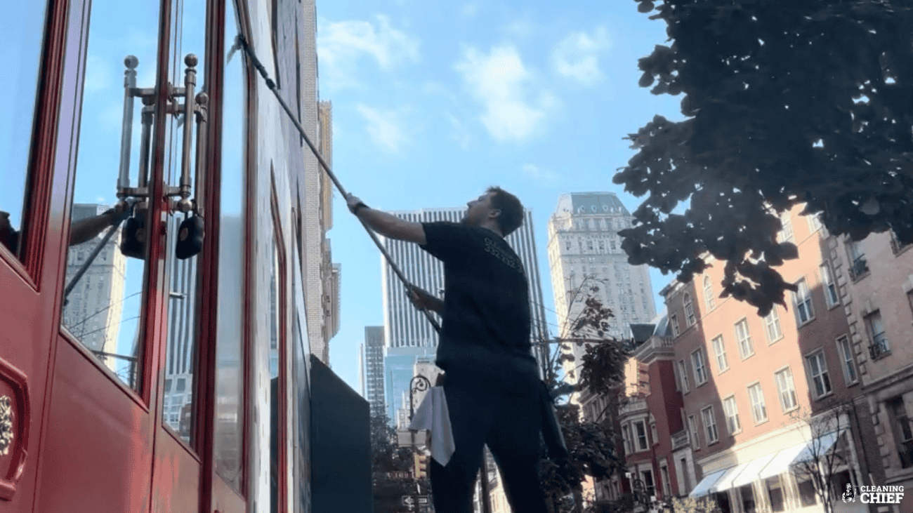 Window cleaner wiping large glass storefront in New York City for a streak-free finish