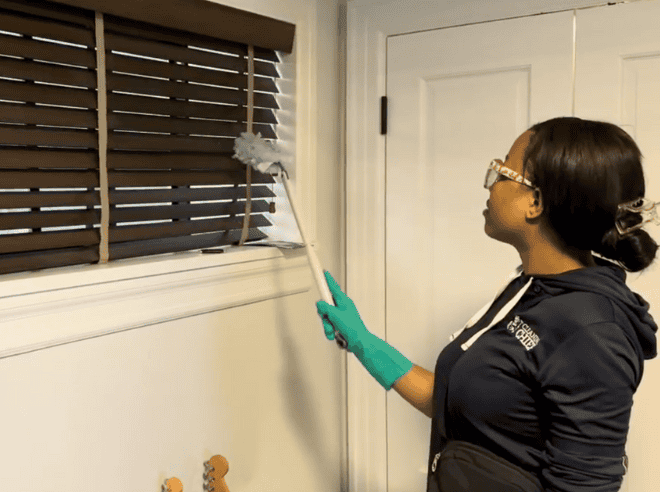 Professional house cleaner expertly cleaning window blind