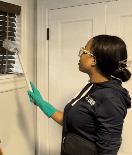 Housekeeping maid gently dusting interior window surfaces. Daily residential cleaning for a brighter, healthier home.